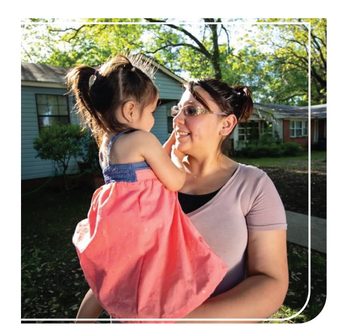 Hispanic mother smiling and holding  daughter outside